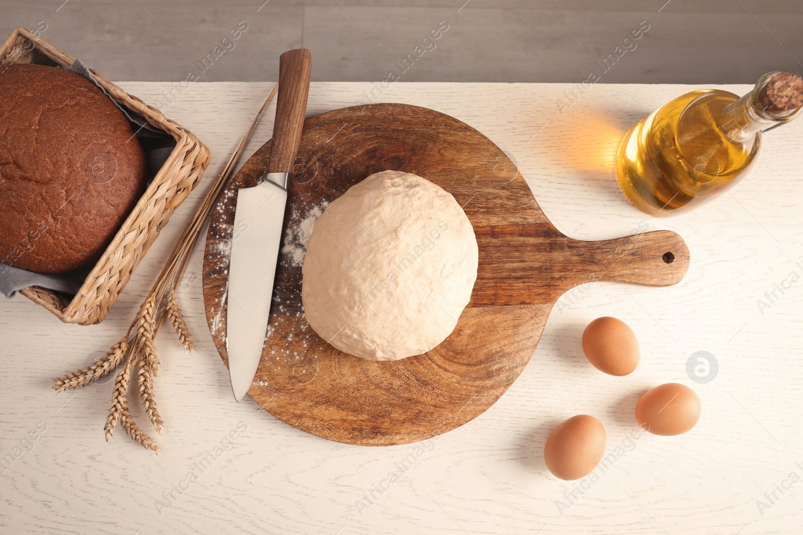 Photo of Fresh dough sprinkled with flour and other ingredients on white wooden table, flat lay