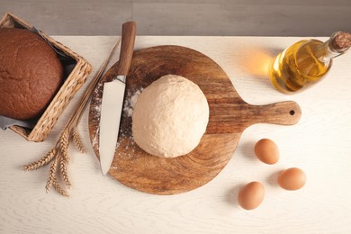 Fresh dough sprinkled with flour and other ingredients on white wooden table, flat lay