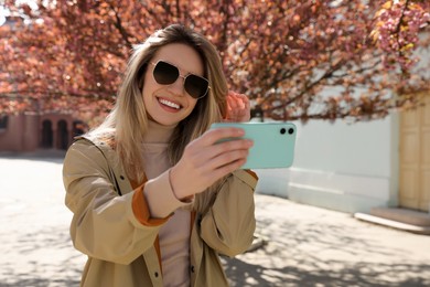 Photo of Young woman taking selfie on city street