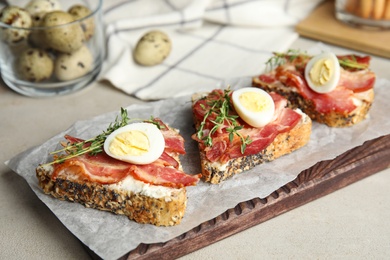 Photo of Cutting board of delicious bruschettas with prosciutto on table