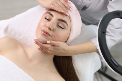 Photo of Cosmetologist making face massage to client in clinic, above view