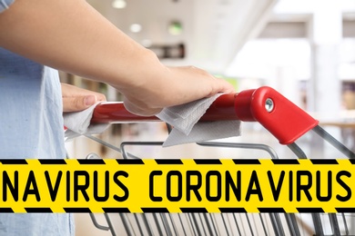 Image of Preventive measure in public places during coronavirus outbreak. Woman holding shopping cart handle with tissue paper at supermarket, closeup 
