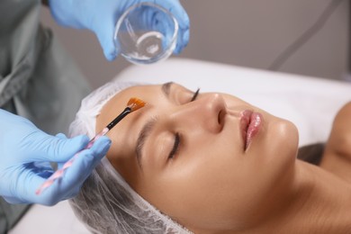 Photo of Cosmetologist applying chemical peel product on client's face in salon