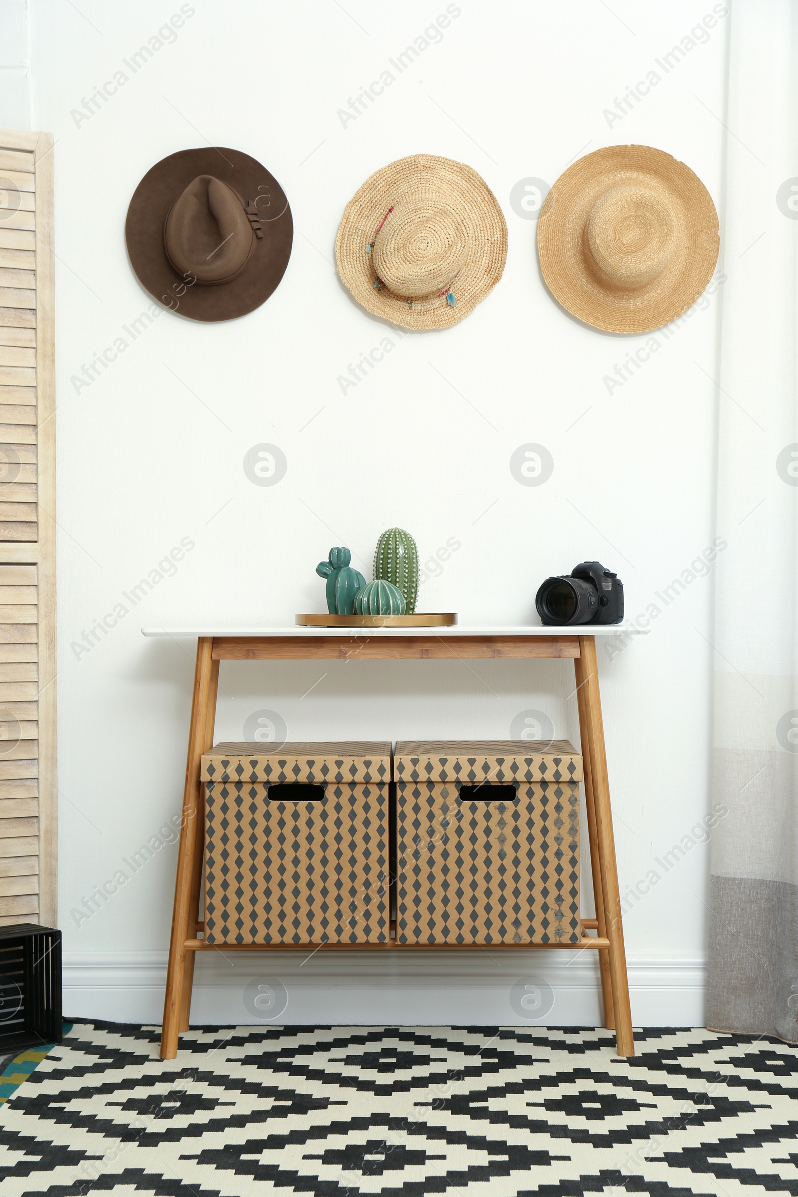 Photo of Stylish wooden table with boxes at white wall in room