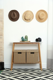 Photo of Stylish wooden table with boxes at white wall in room