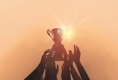 Image of People with gold trophy cup on color background, closeup