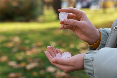 Photo of Woman holding hail grains after thunderstorm in park, closeup