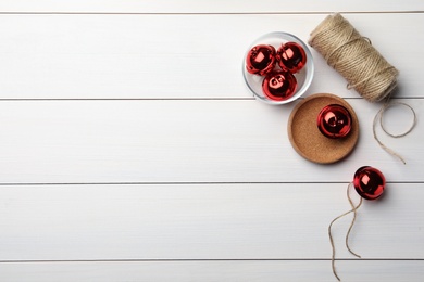 Photo of Red sleigh bells and rope on white wooden background, flat lay. Space for text