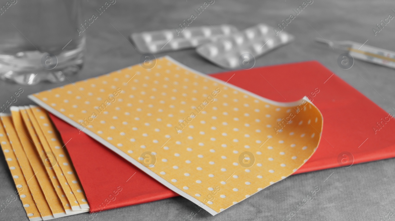 Photo of Pepper plasters and pills on grey textured background, closeup