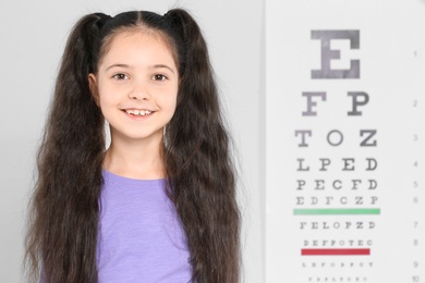 Photo of Portrait of cute little girl visiting children's doctor, space for text. Eye examination