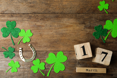 Photo of Flat lay composition with clover leaves and block calendar on wooden background, space for text. St. Patrick's day