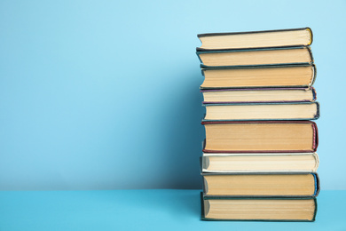 Stack of hardcover books on light blue background, space for text