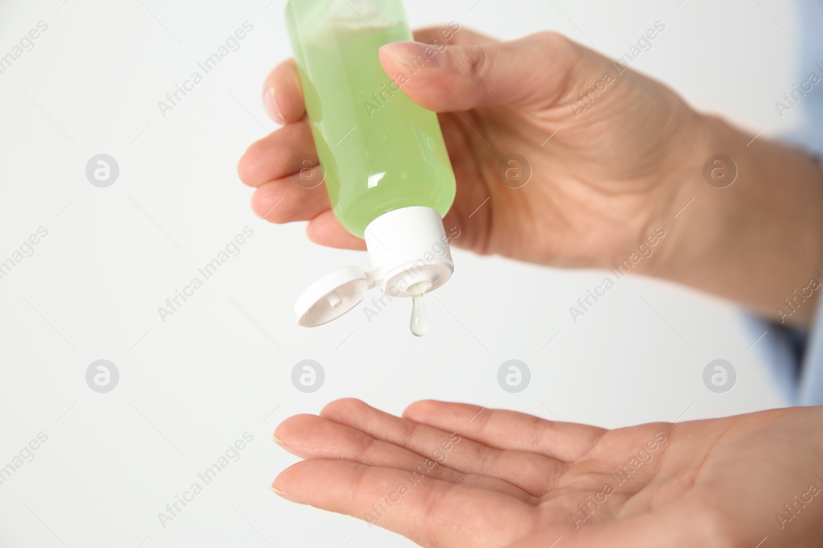 Photo of Woman applying antiseptic gel on light background, closeup