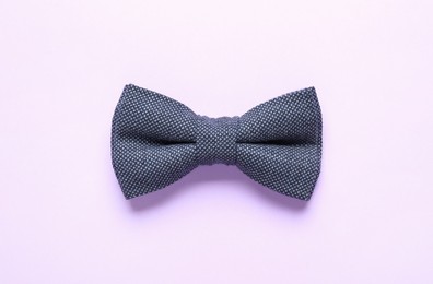 Stylish bow tie on lilac background, top view