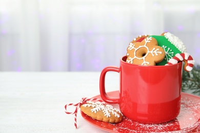 Photo of Cup with tasty homemade Christmas cookies on table