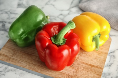 Wooden board with ripe paprika peppers on table