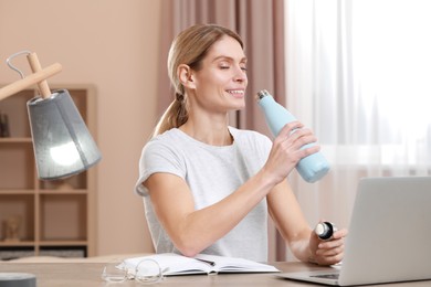 Woman with thermo bottle at workplace in room