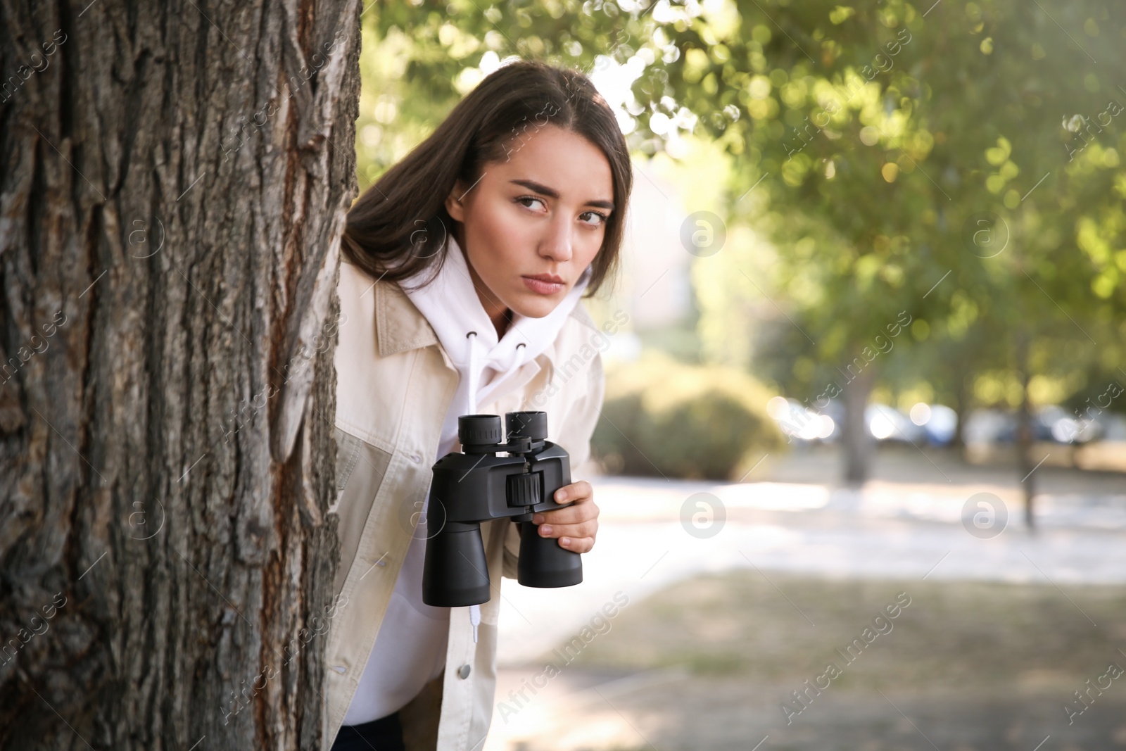 Photo of Jealous woman with binoculars spying on ex boyfriend in park