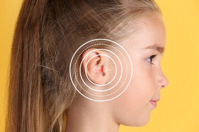 Image of Cute little girl with hearing problem on yellow background, closeup