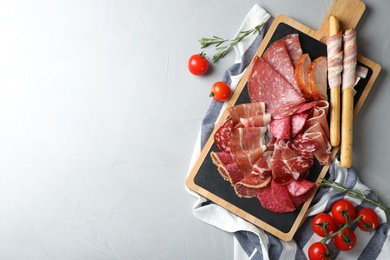 Photo of Different meat delicacies served on gray table, top view. Space for text