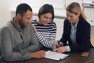 Professional notary helping couple with paperwork in office