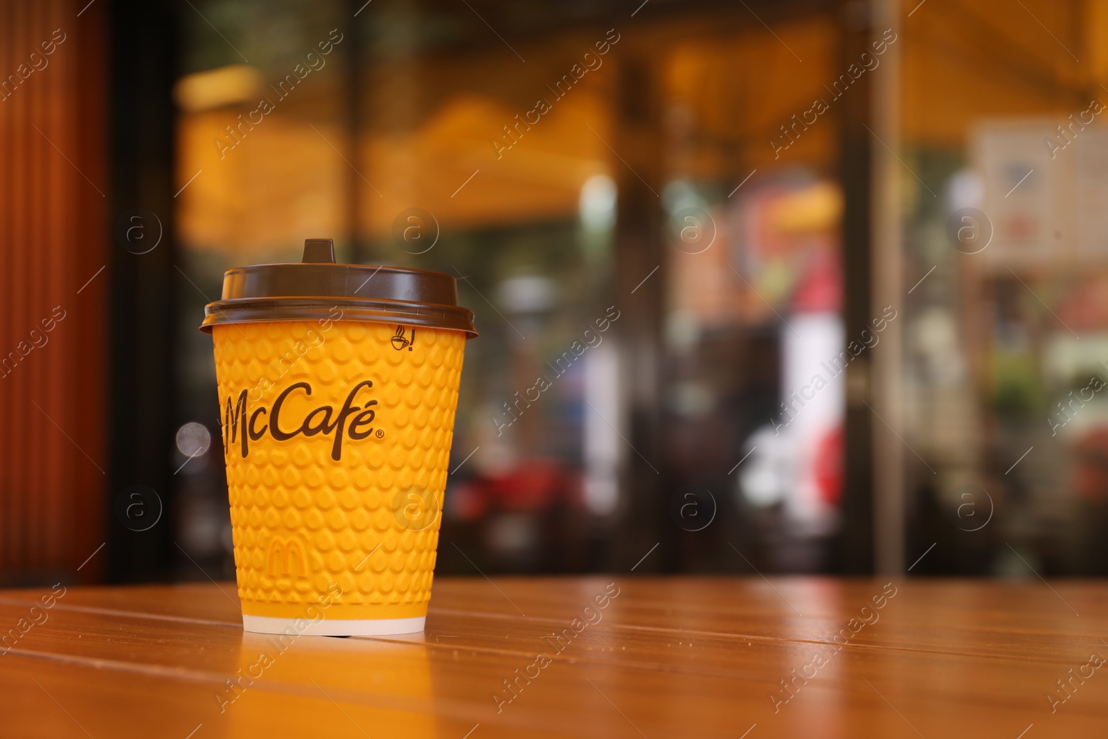 Photo of MYKOLAIV, UKRAINE - AUGUST 11, 2021: Hot McDonald's drink on table in cafe. Space for text