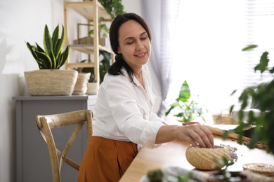 Mature woman potting plant at home. Engaging hobby