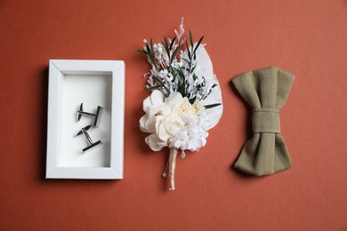 Photo of Wedding stuff. Stylish boutonniere, bow tie and cufflinks on brown background
