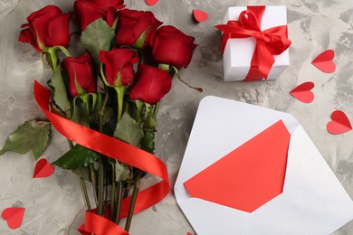 Flat lay composition with beautiful red roses, love letter and gift box on light grey background. Valentine's Day celebration