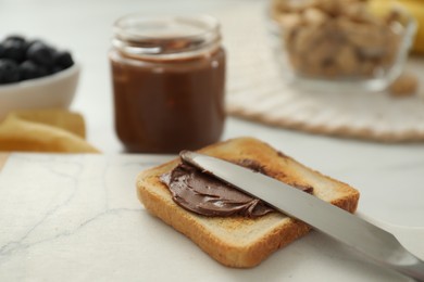 Photo of Toast with tasty nut butter and knife on white table, closeup