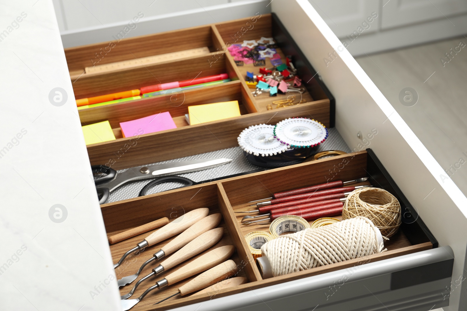 Photo of Sewing accessories and stationery in open desk drawer indoors