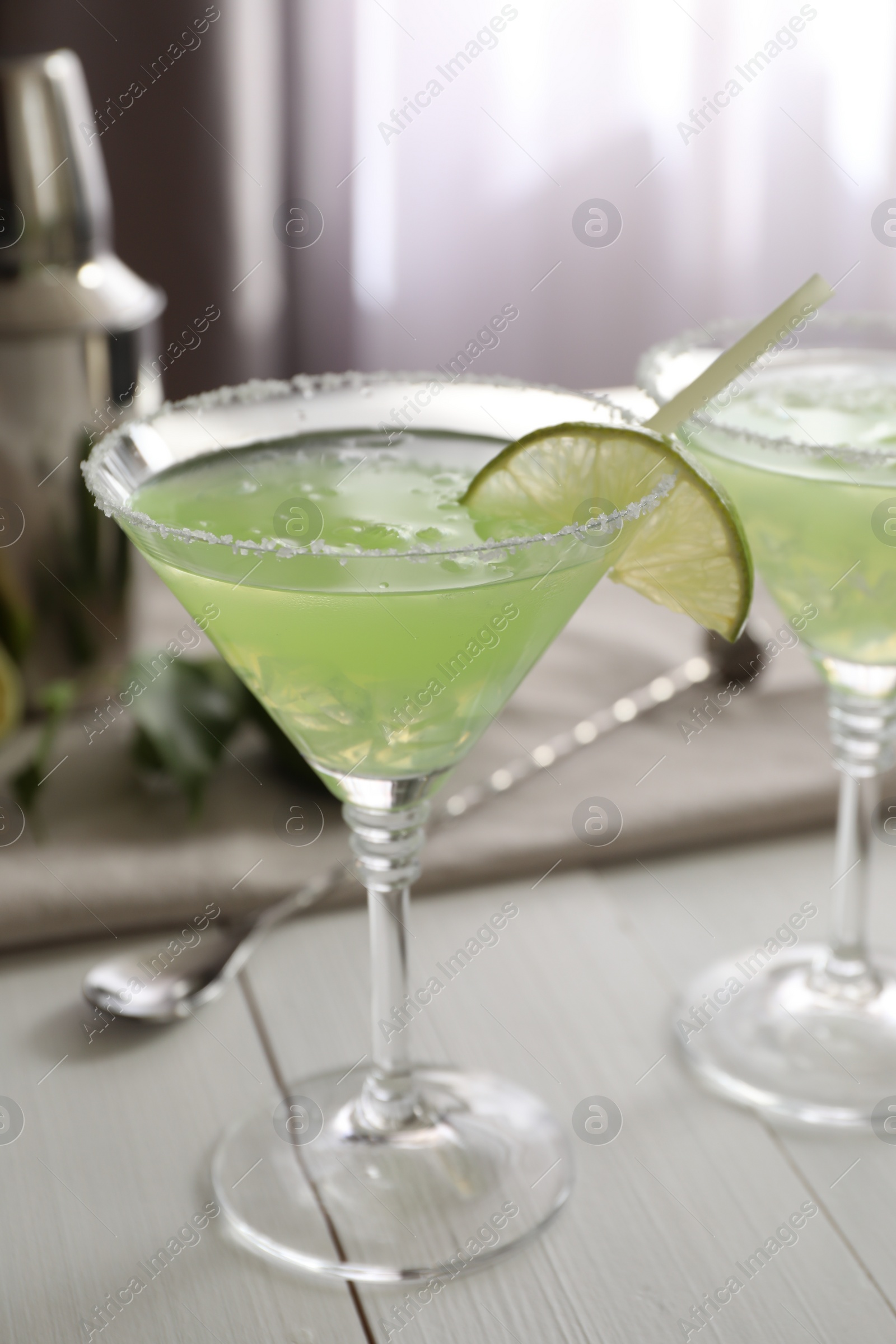 Photo of Delicious Margarita cocktail in glasses and lime on white wooden table