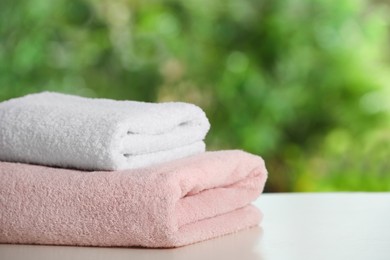 Photo of Folded towels on white table against blurred background, space for text