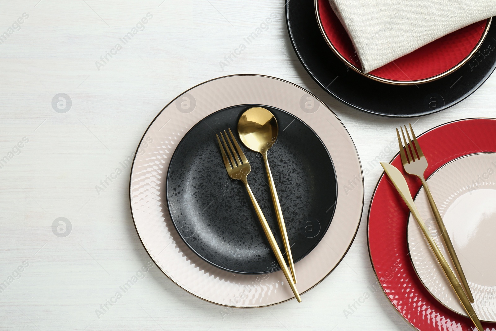 Photo of Stylish ceramic plates, cutlery and napkin on white wooden table, flat lay