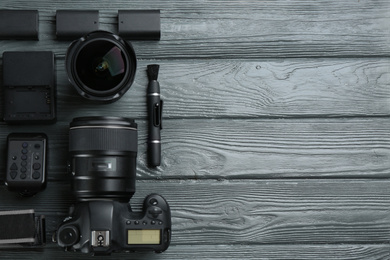 Photo of Flat lay composition with equipment for professional photographer on grey wooden table. Space for text