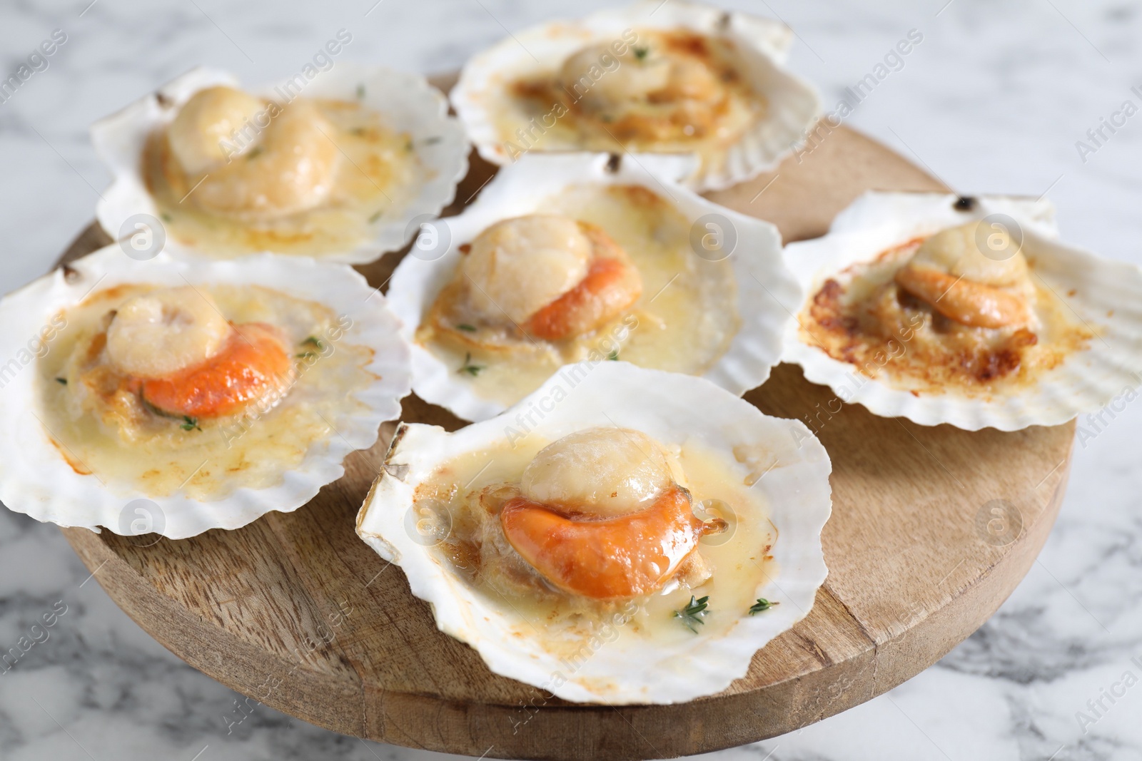 Photo of Fried scallops in shells on white marble table, closeup