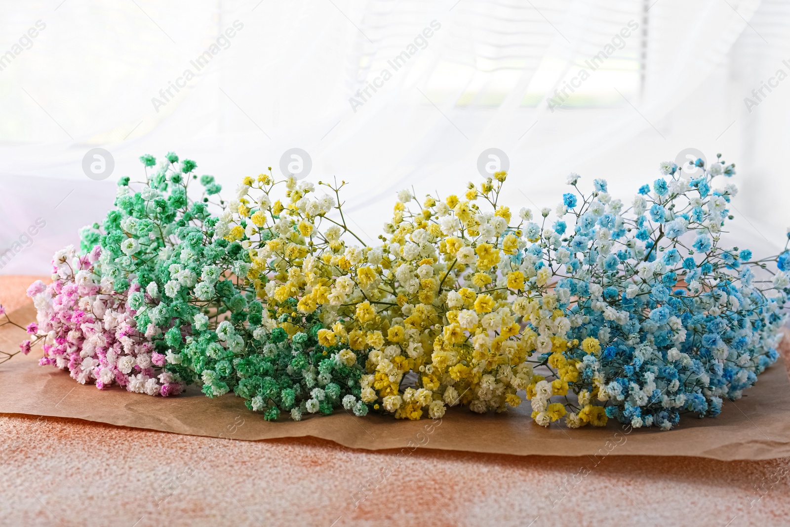 Photo of Beautiful gypsophila flowers on textured table near window