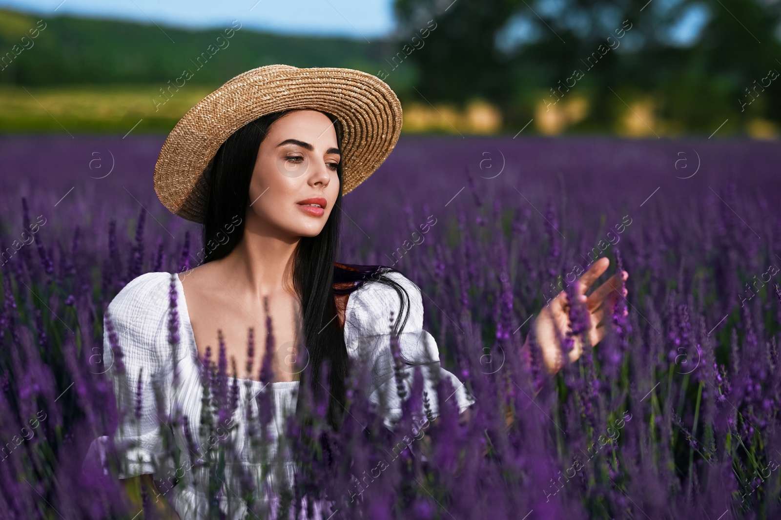 Photo of Beautiful young woman with straw hat in lavender field