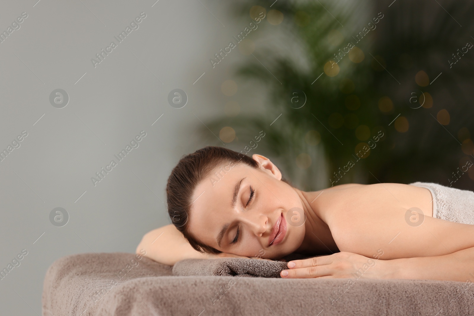 Photo of Beautiful young woman relaxing in spa salon. Space for text