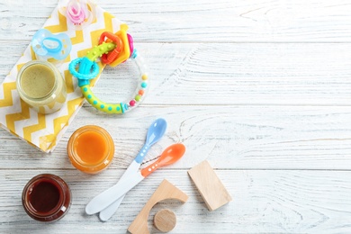 Photo of Flat lay composition with baby food and accessories on wooden background