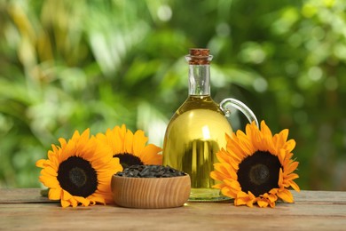 Sunflower cooking oil, seeds and yellow flowers on wooden table outdoors