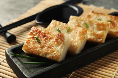 Photo of Delicious turnip cake with green onion on 'mat, closeup