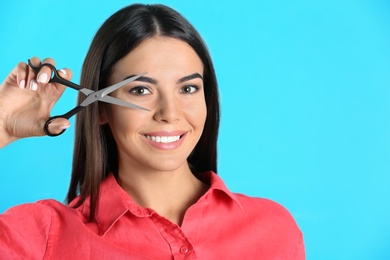 Photo of Young hairstylist holding professional scissors on color background, space for text