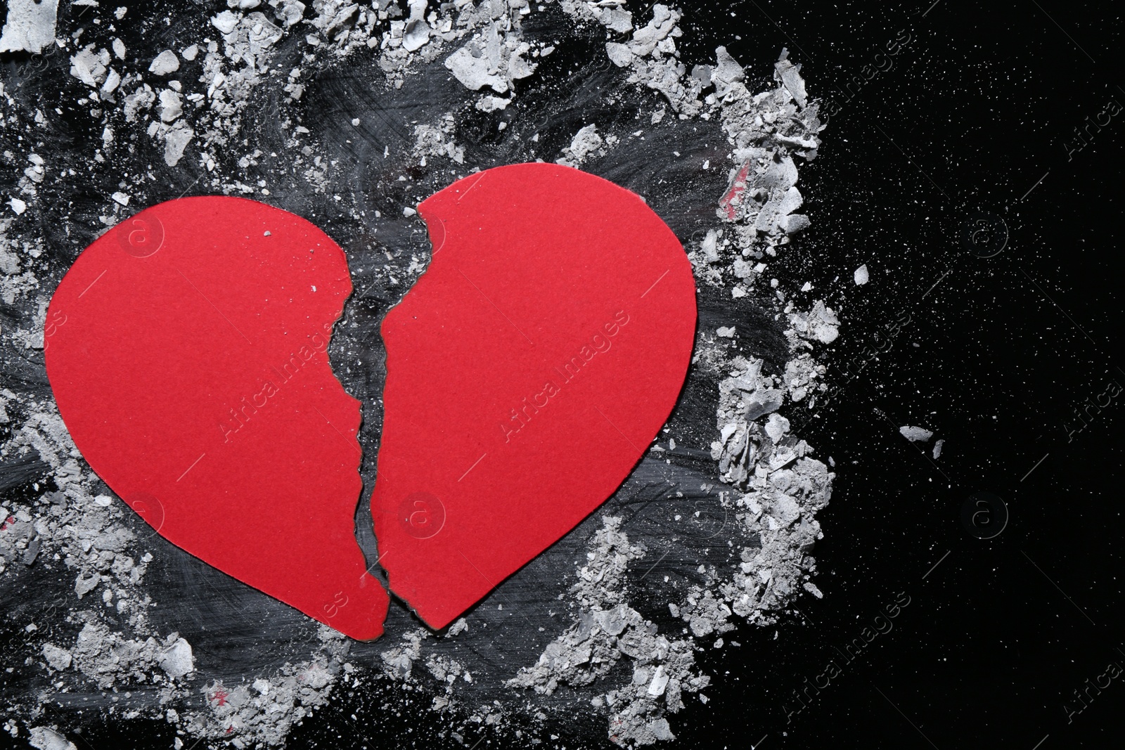 Photo of Halves of torn paper heart and ash on black background, top view