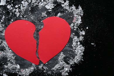Photo of Halves of torn paper heart and ash on black background, top view