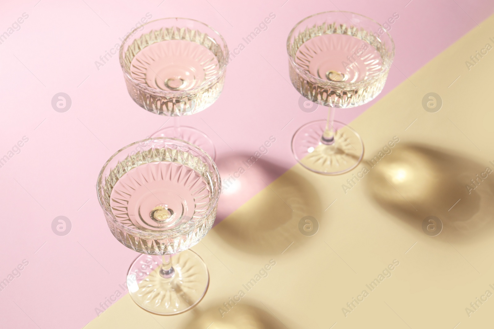 Photo of Glasses of expensive white wine on color background
