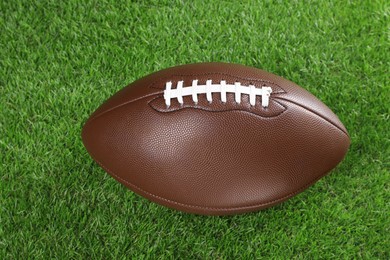 Photo of American football ball on green grass, closeup