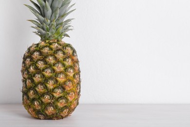 Photo of Whole ripe pineapple on white wooden table. Space for text