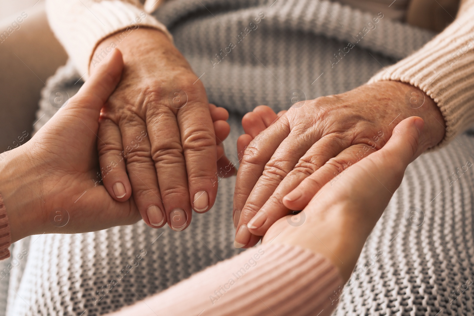 Photo of Young and elderly women holding hands together, closeup