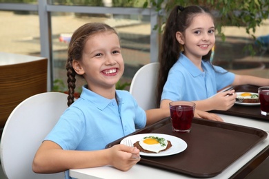 Cute children at table with healthy food in school canteen